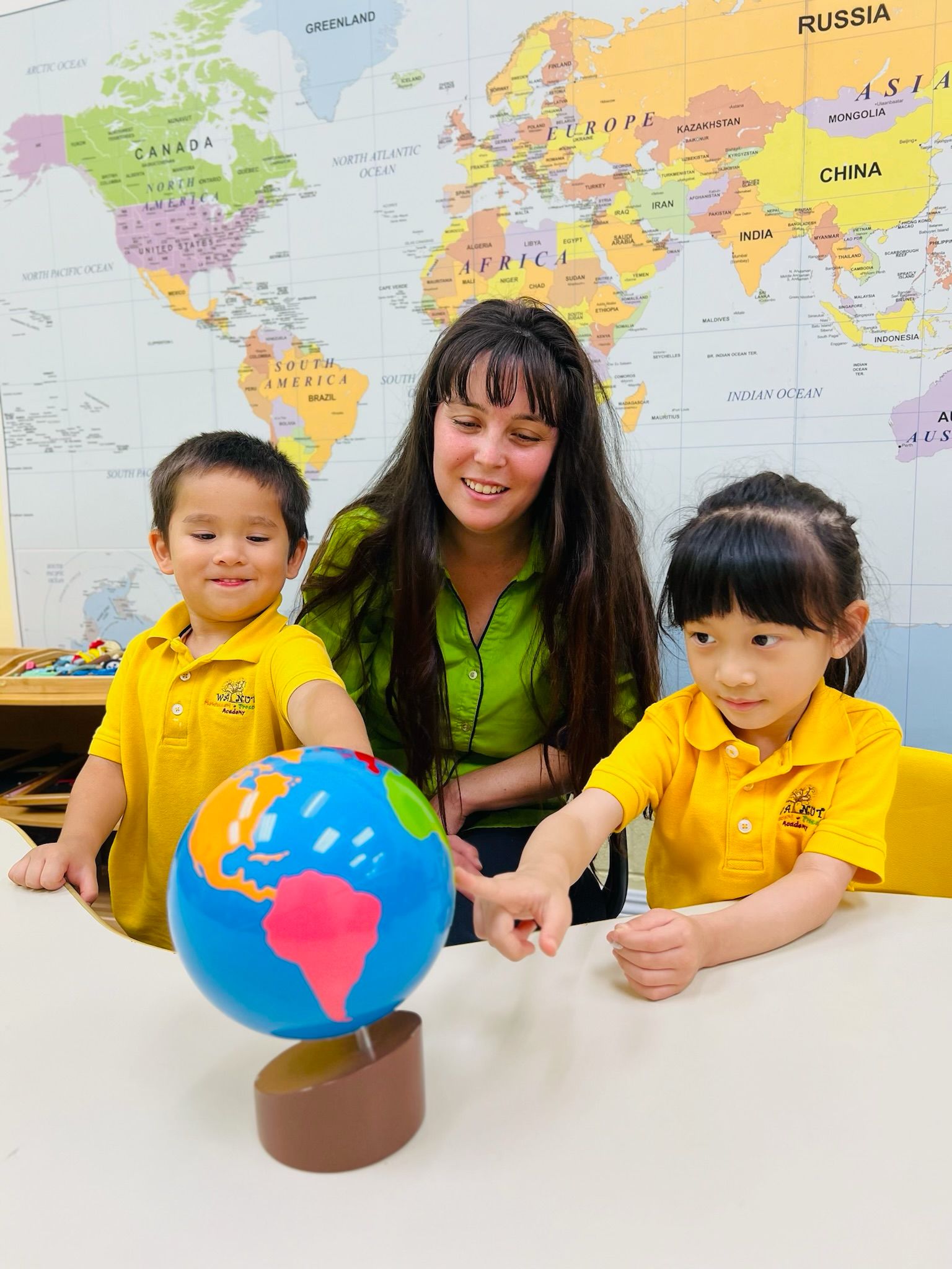 Teacher and children exploring a globe at Walnut Montessori Academy